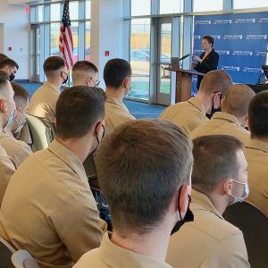 Tombs Lecture Series 2 DuLong behind a podium speaking before an audience of young men in beige uniforms